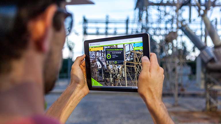 Electrical worker using mobile application to monitor substation equipment.